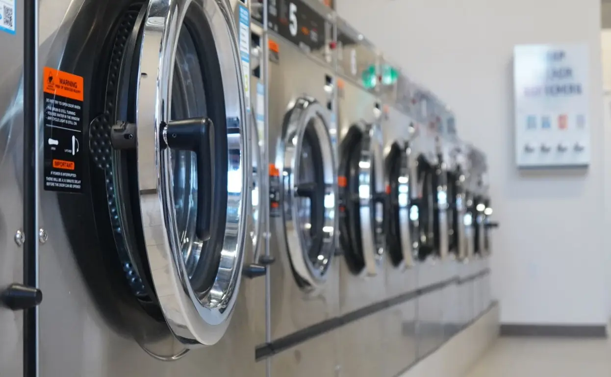 A long row of stainless-steel front-load washers inside Beaumont Laundromat